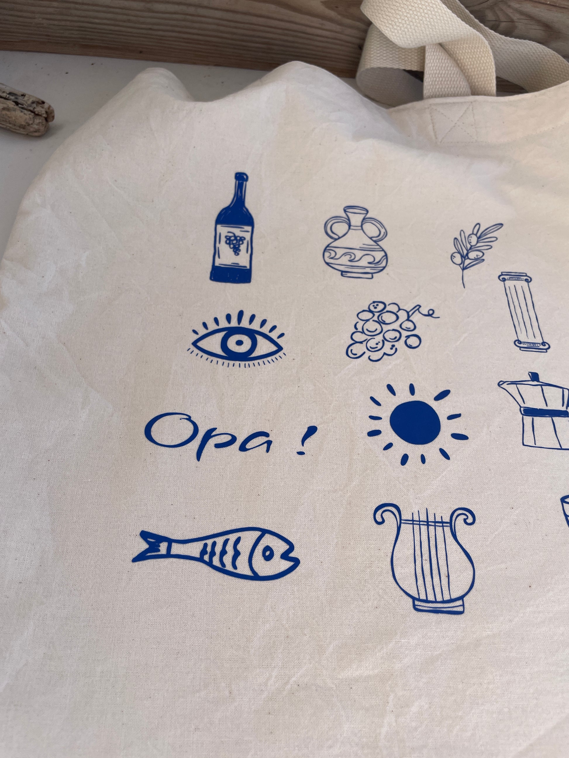 White tote bag with blue Mediterranean-themed illustrations and text.