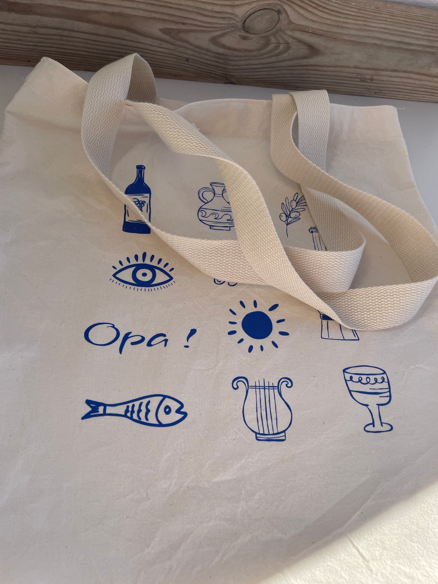 Beige tote bag with blue icons and text on a white surface