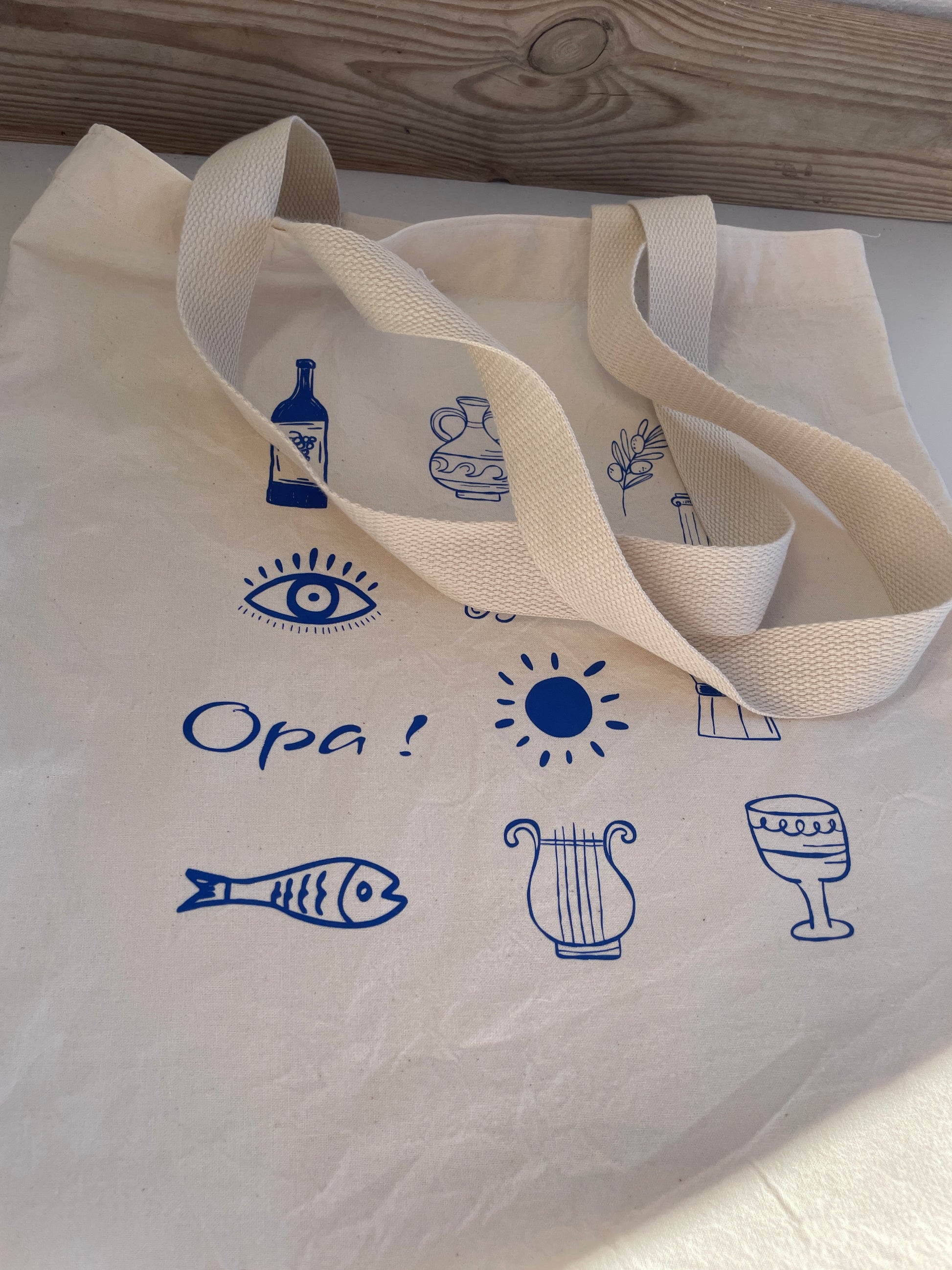 Beige tote bag with blue icons and text on a white surface