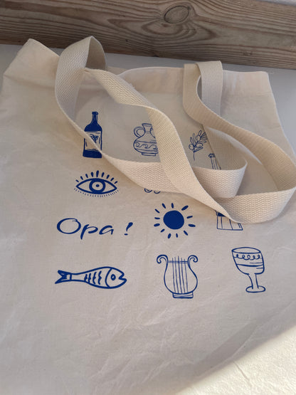 Beige tote bag with blue icons and text on a white surface