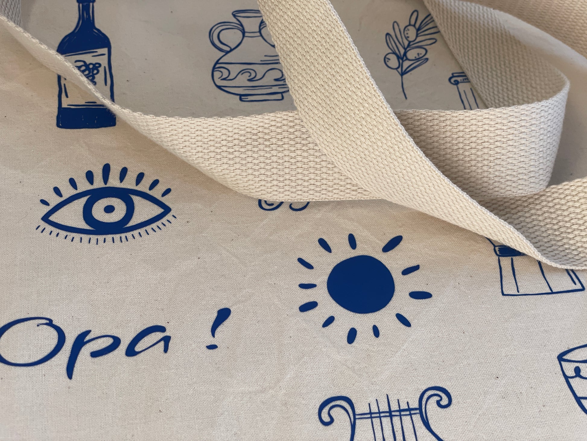 Close-up of fabric with blue printed designs including an eye, sun, and text on a white background.