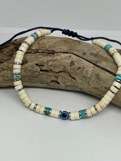 Beaded necklace with blue and turquoise accents on a piece of driftwood against a white background