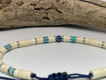 Necklace with white and blue beads on a white surface with wooden background