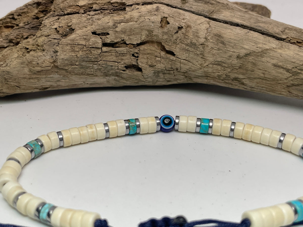 Beaded bracelet with blue and silver accents on a white surface with driftwood.