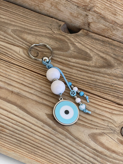 Keychain with blue evil eye charm on a wooden surface