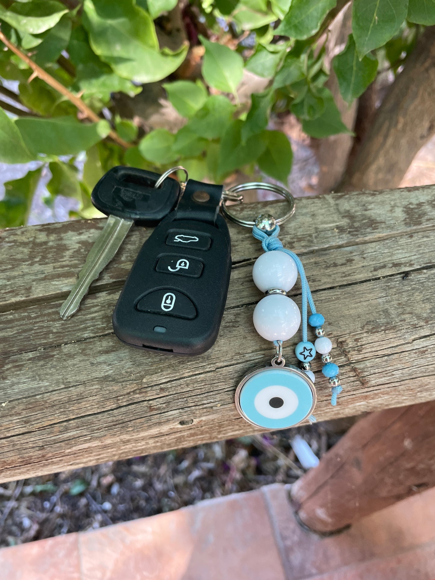 Keychain with beads and a key fob attached to a wooden post outdoors