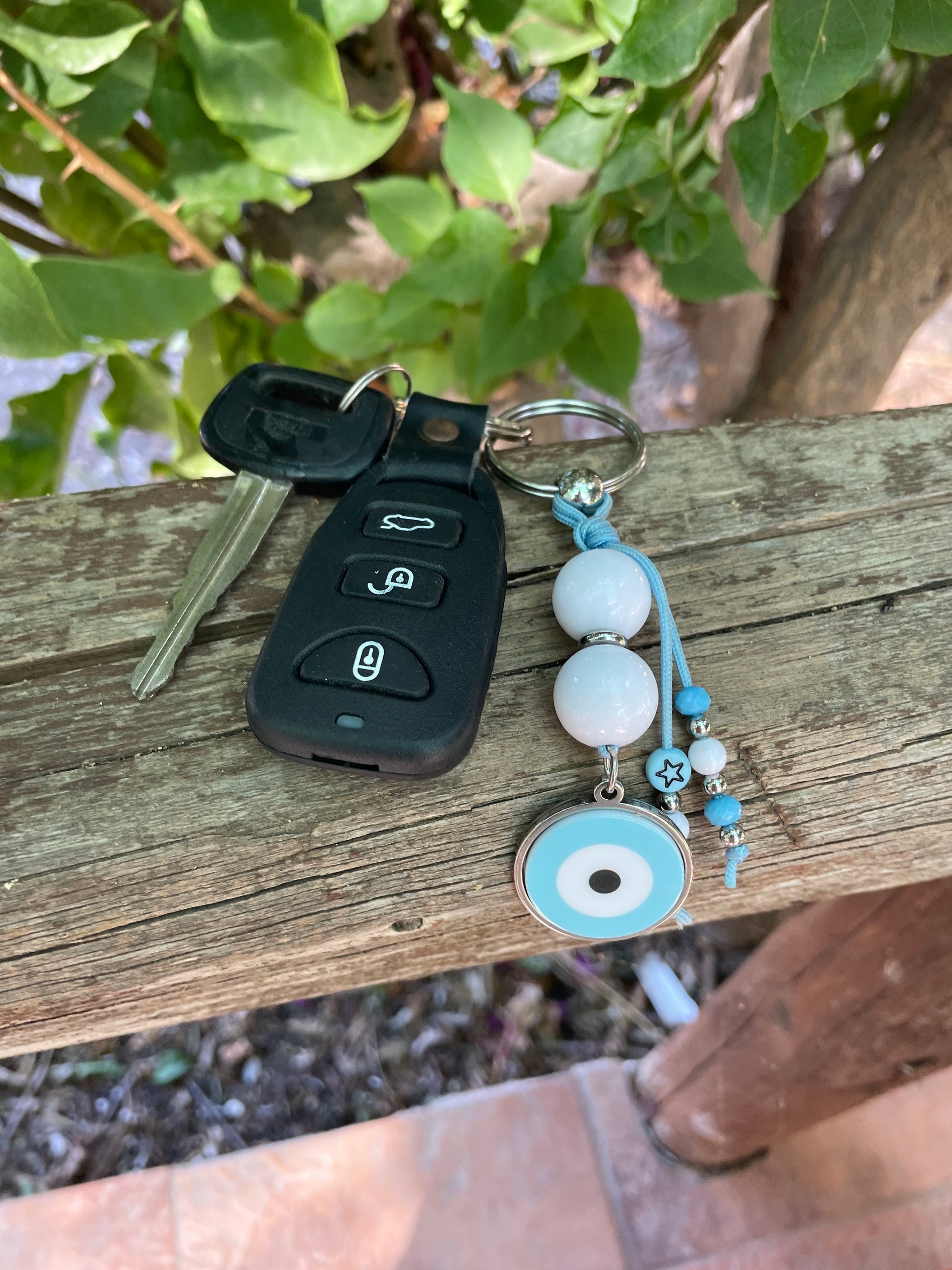 Keychain with beads and a key fob attached to a wooden post outdoors