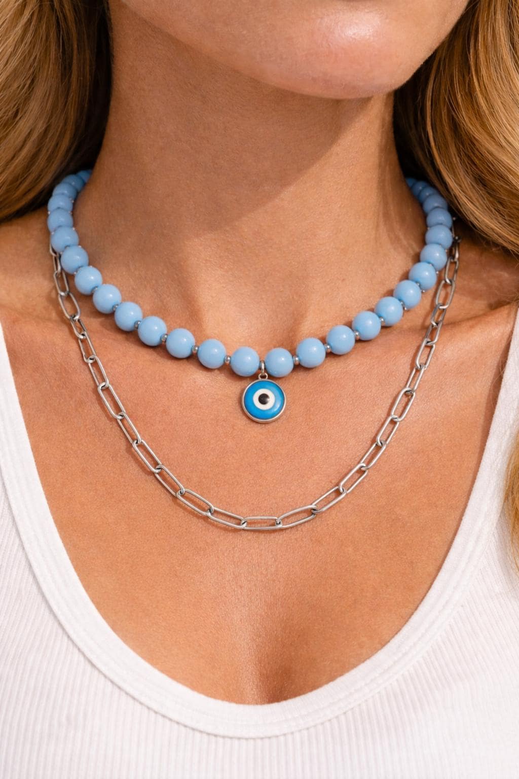 Necklace with blue beads and a silver chain worn by a person