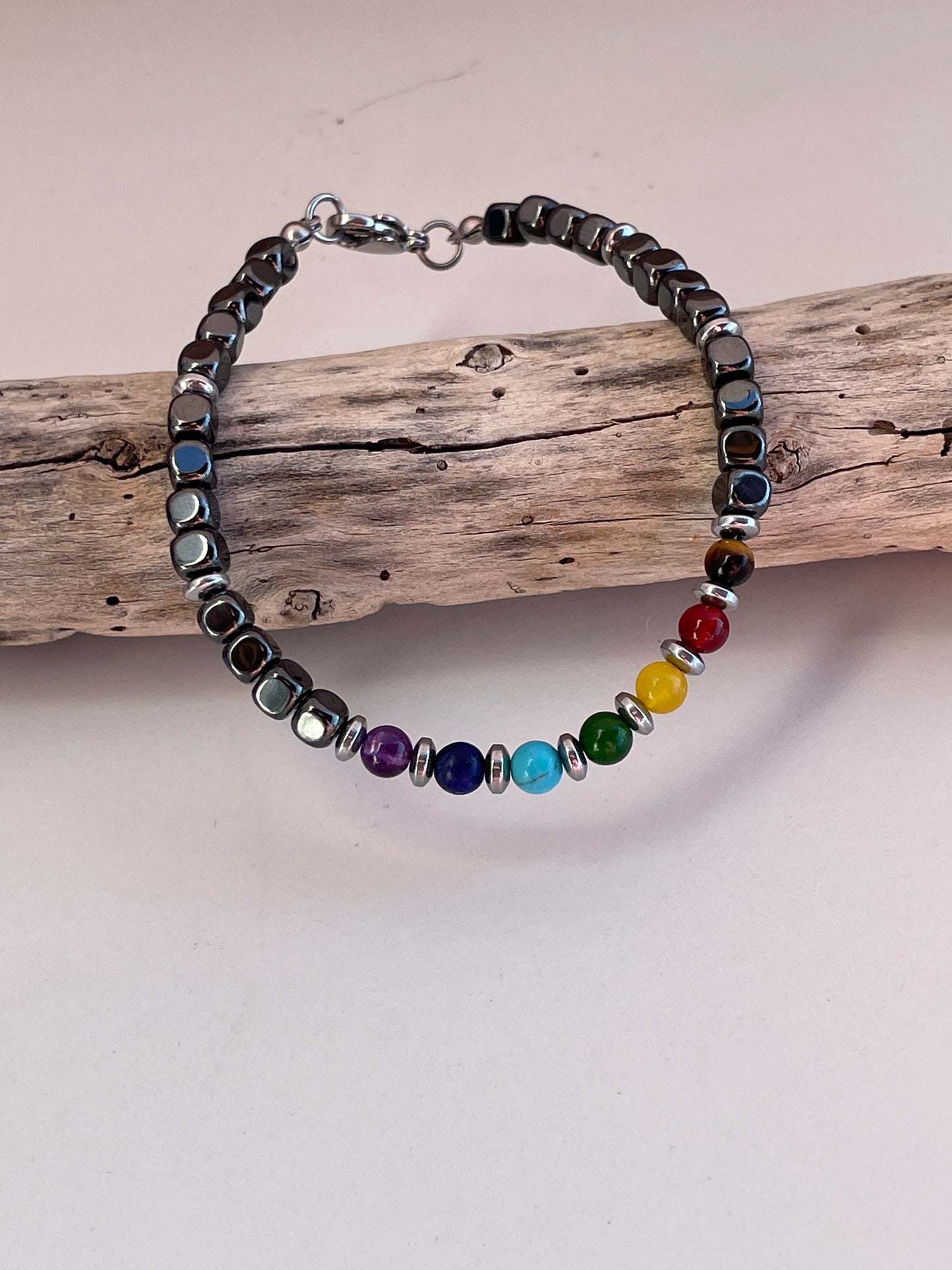 Bracelet with colorful beads on a wooden stick against a plain background