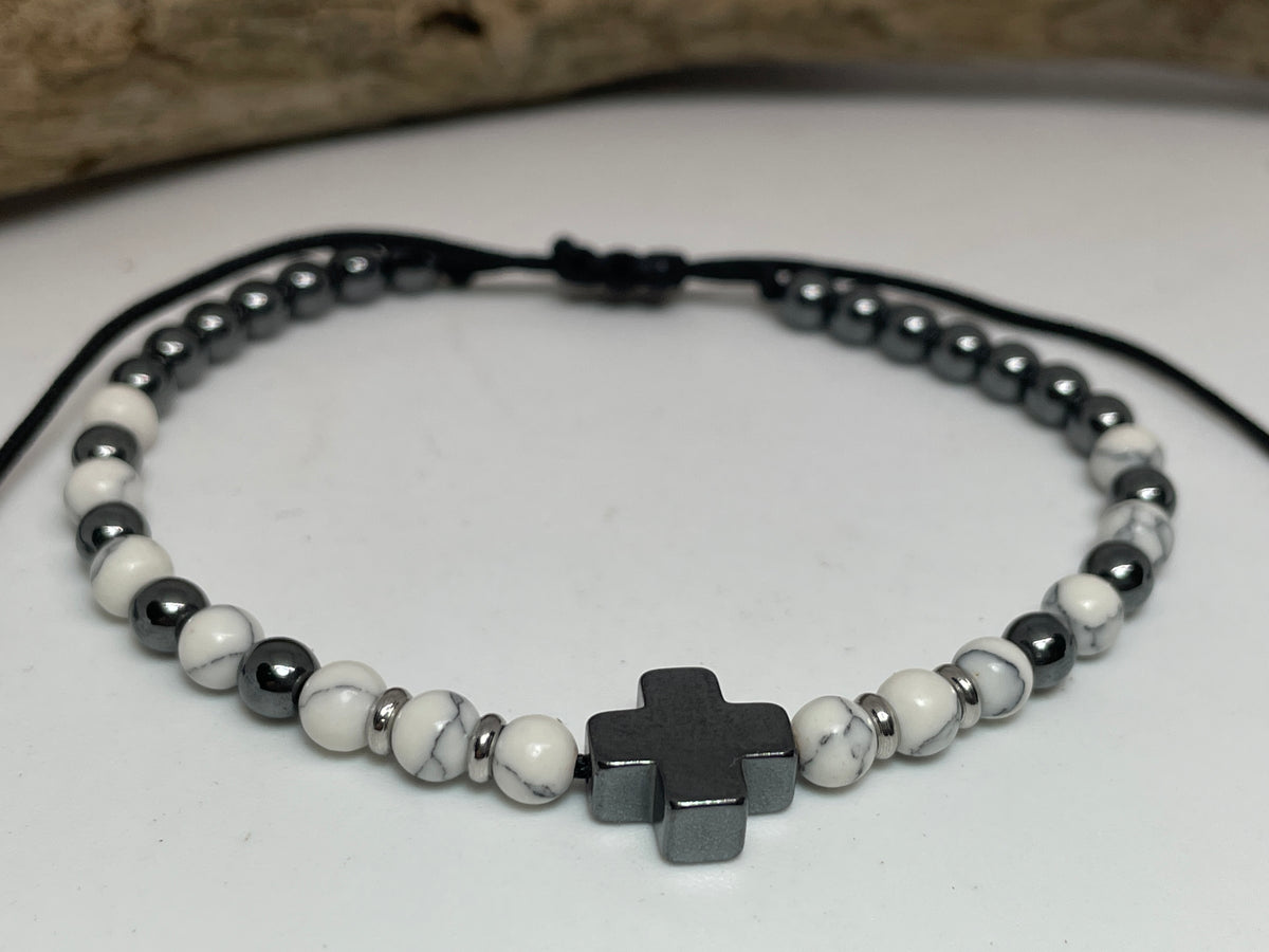 Beaded bracelet with a cross charm on a white surface
