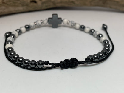 Bracelet with black and white beads and a cross charm on a light background
