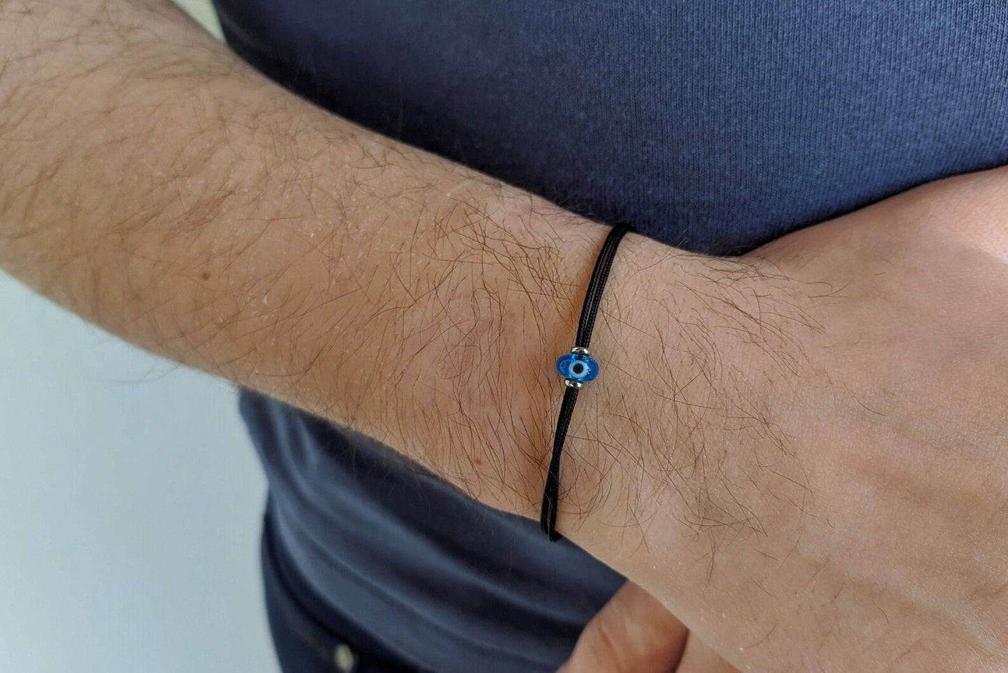 Close-up of a wrist wearing a black bracelet with a blue bead.