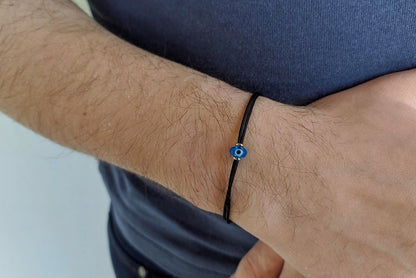 Close-up of a wrist wearing a black bracelet with a blue bead.