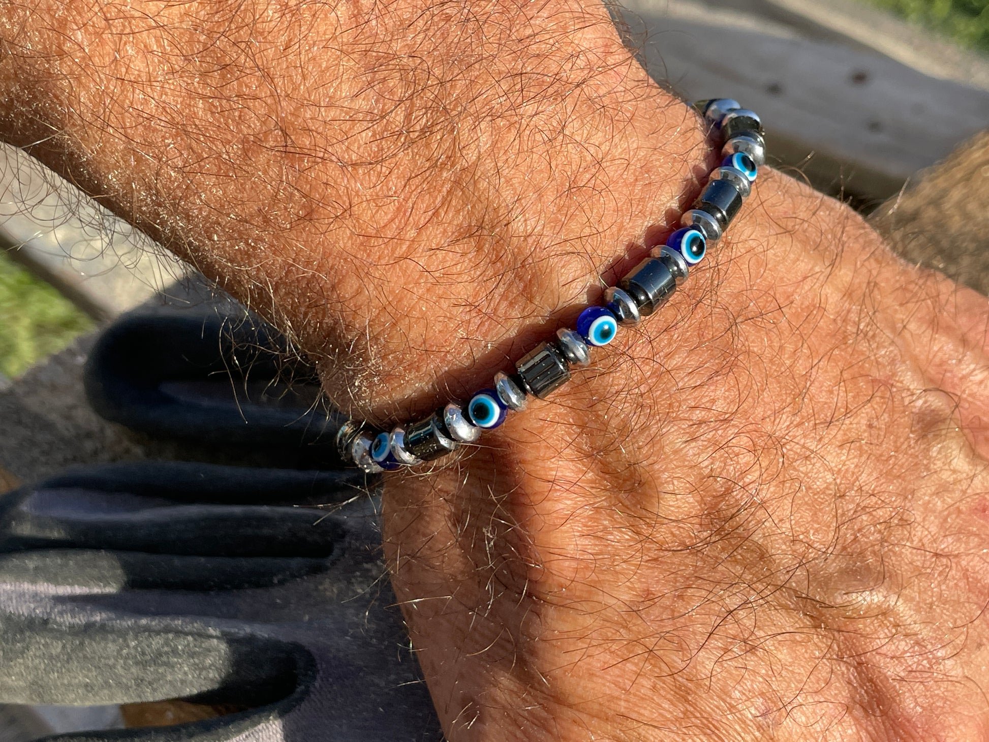 Close-up of a wrist wearing a beaded bracelet with blue eye beads.