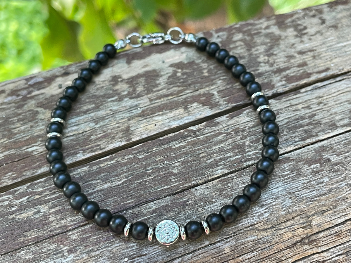 Black beaded bracelet with a silver clasp on a wooden surface