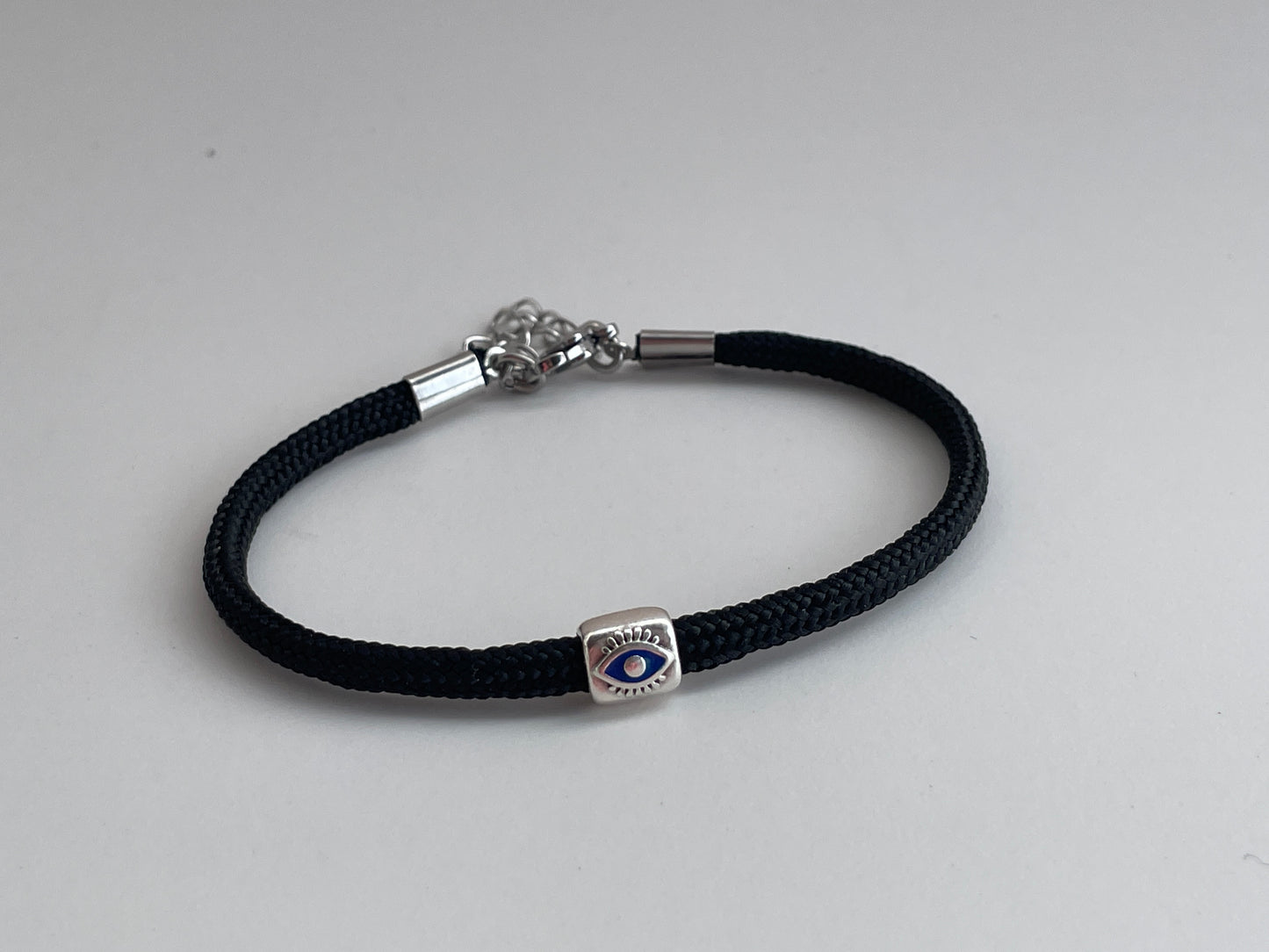 Black braided bracelet with a silver clasp on a light gray background