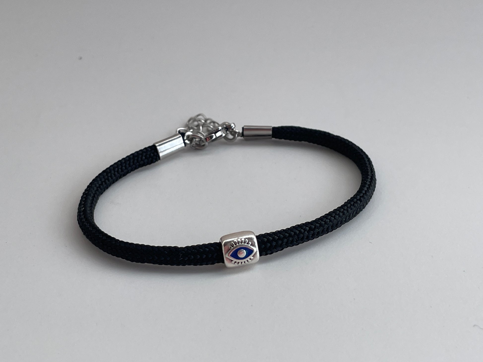 Black braided bracelet with a silver clasp on a light gray background
