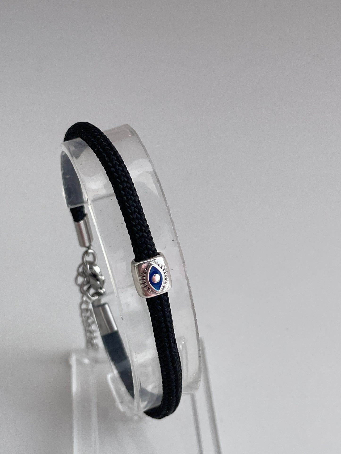 Black bracelet with a silver clasp on a clear stand against a gray background
