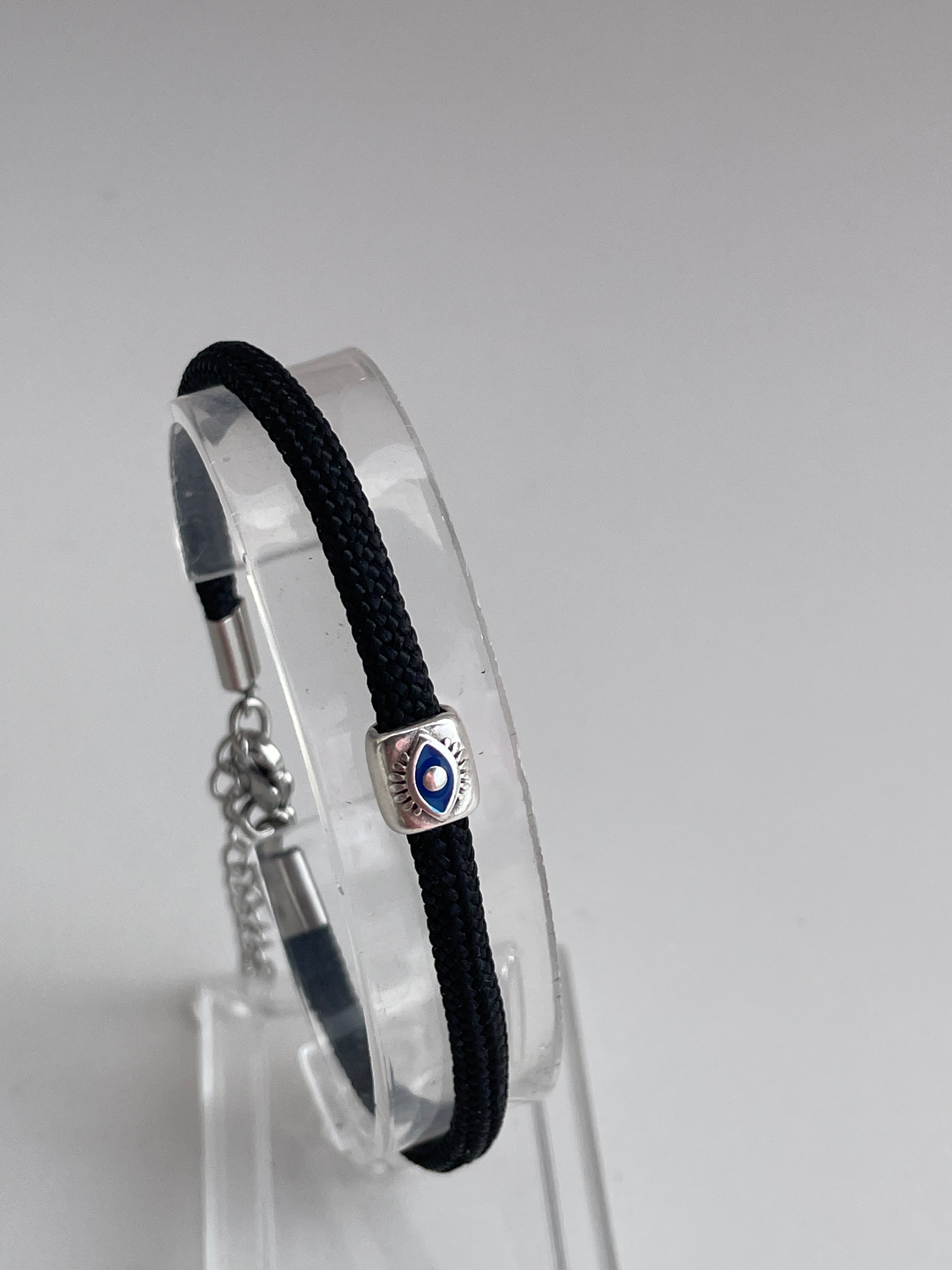 Black bracelet with a silver clasp on a clear stand against a gray background