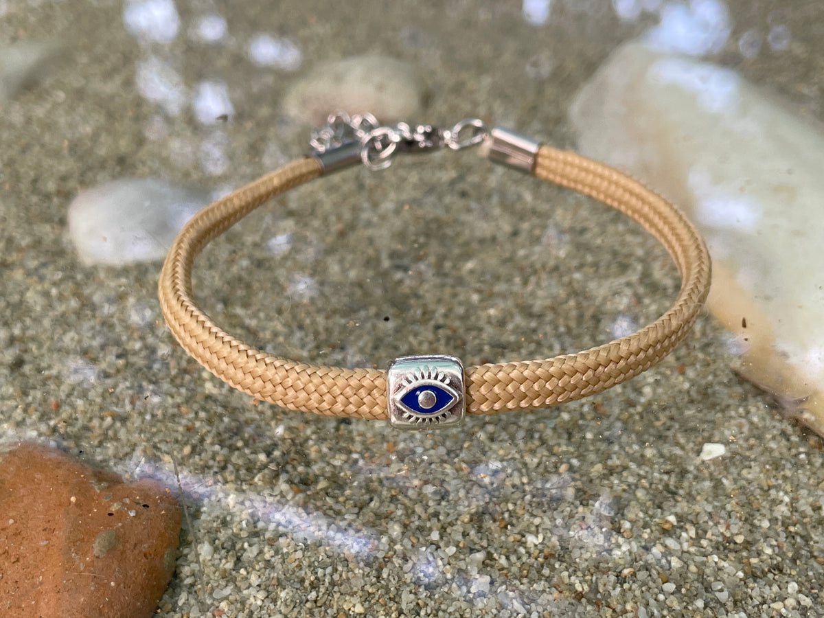 Bracelet with a blue evil eye charm on a sandy surface