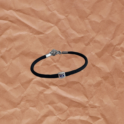 Black leather bracelet with a silver clasp on a brown textured background