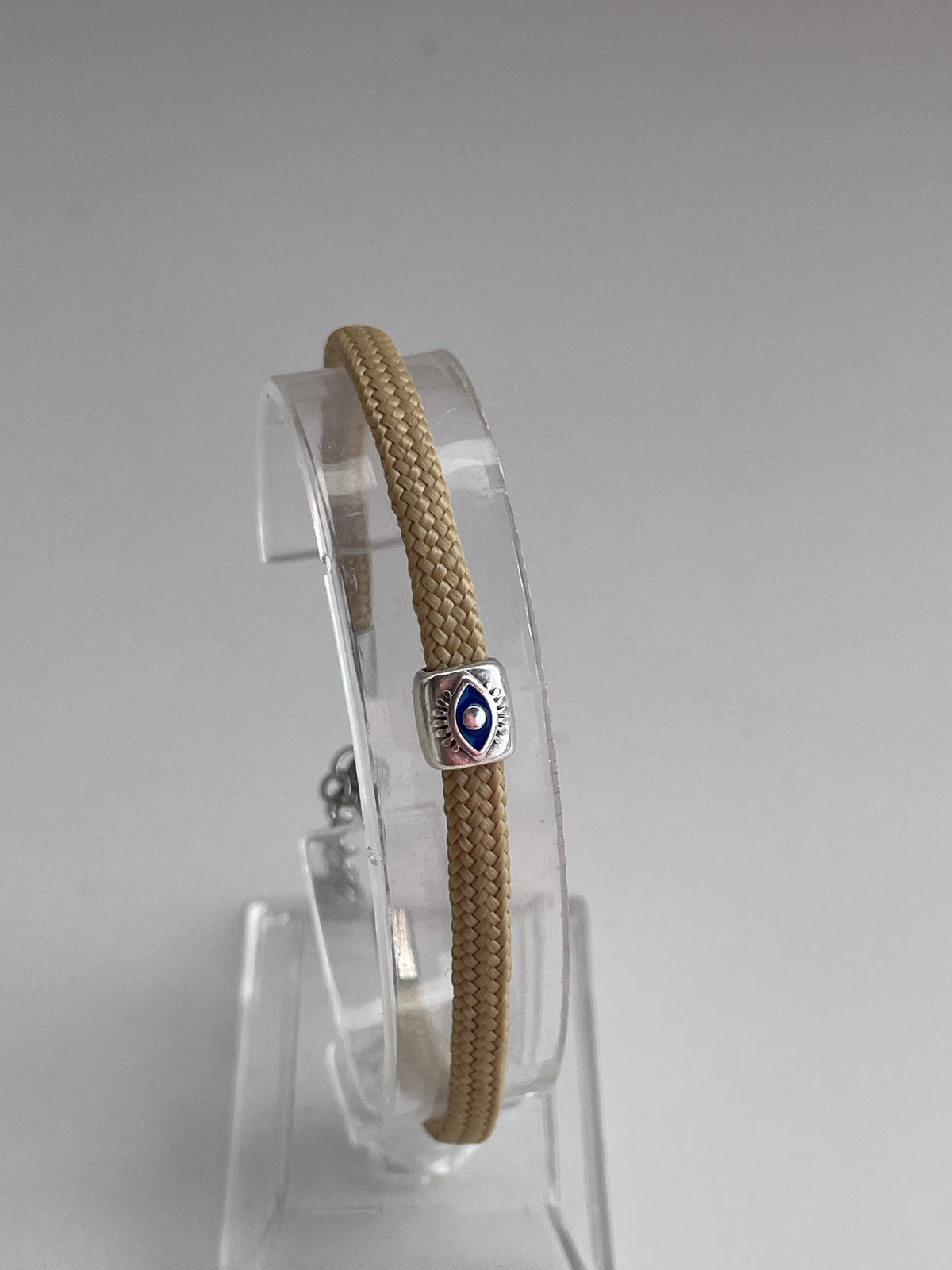 Bracelet with a silver clasp on a clear stand against a gray background