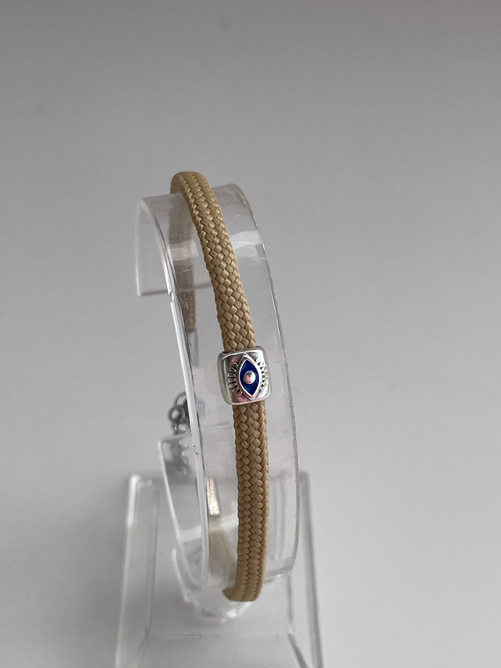 Bracelet with a silver clasp on a clear stand against a gray background