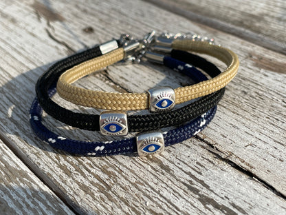 Triple-layered bracelet with eye-shaped charms on a wooden surface