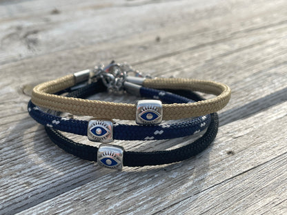 Stack of woven bracelets with eye-shaped charms on a wooden surface