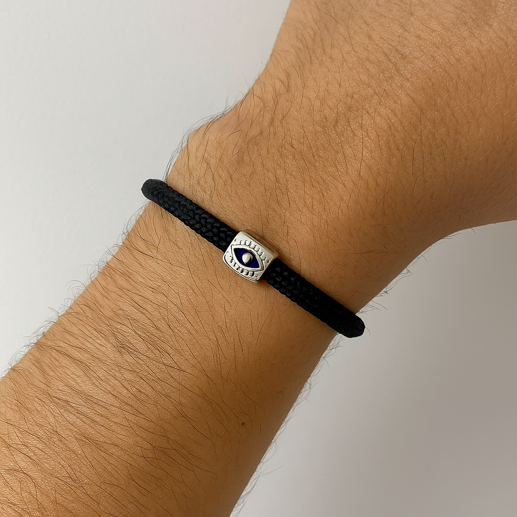 Black bracelet with an eye symbol on a wrist against a neutral background