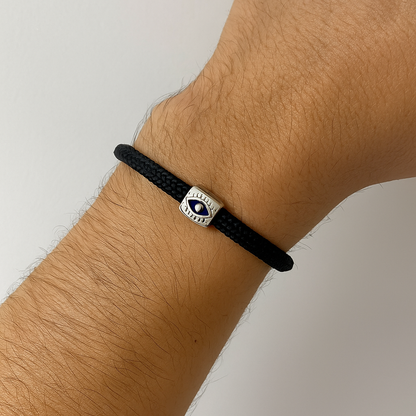 Black bracelet with an eye symbol on a wrist against a neutral background