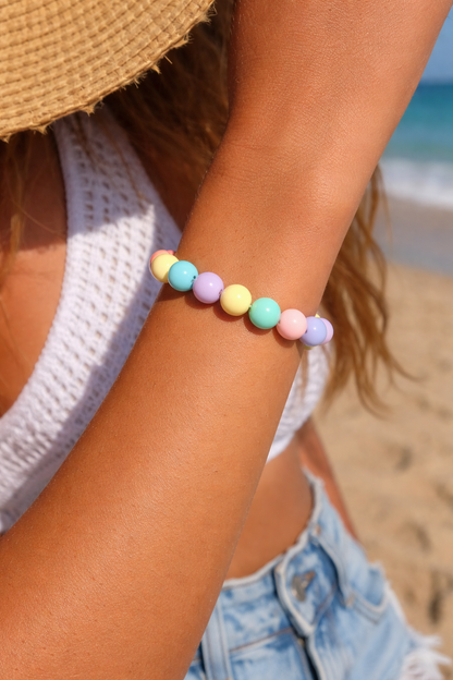 Person wearing a colorful beaded bracelet on a beach