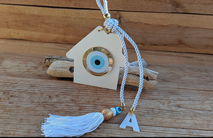 Decorative plexiglass wall hanging with evil eye charm and tassel on a wooden background
