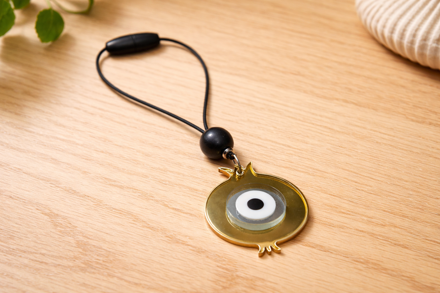 Gold pendant with a black cord on a wooden surface