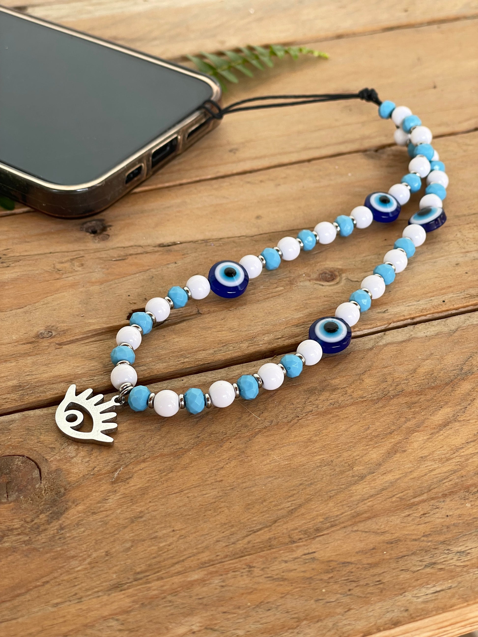 Protective evil eye cellphone strap featuring blue glass eye beads and a beaded wrist lanyard.