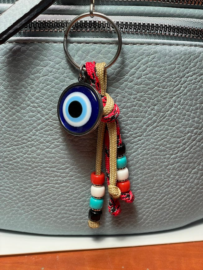 Colorful keychain with an evil eye charm attached to a gray bag.