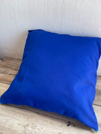 Blue pillow on a wooden surface with a white wall background