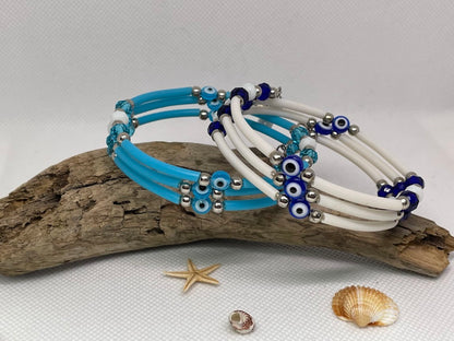 Set of blue and white beaded bracelets on a piece of driftwood with shells and a starfish.