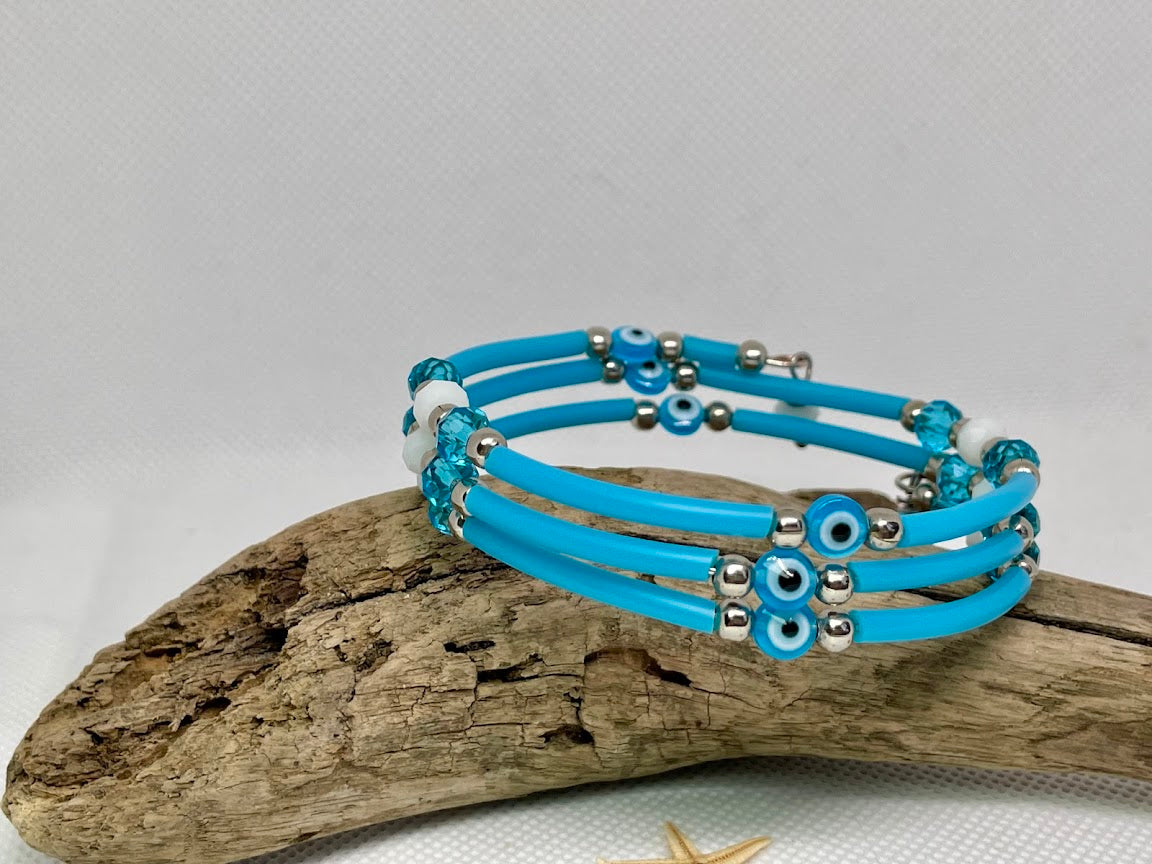 Blue beaded bracelet on a piece of driftwood with a white background