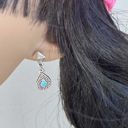 Close-up of an earring with a turquoise stone on a mannequin head.