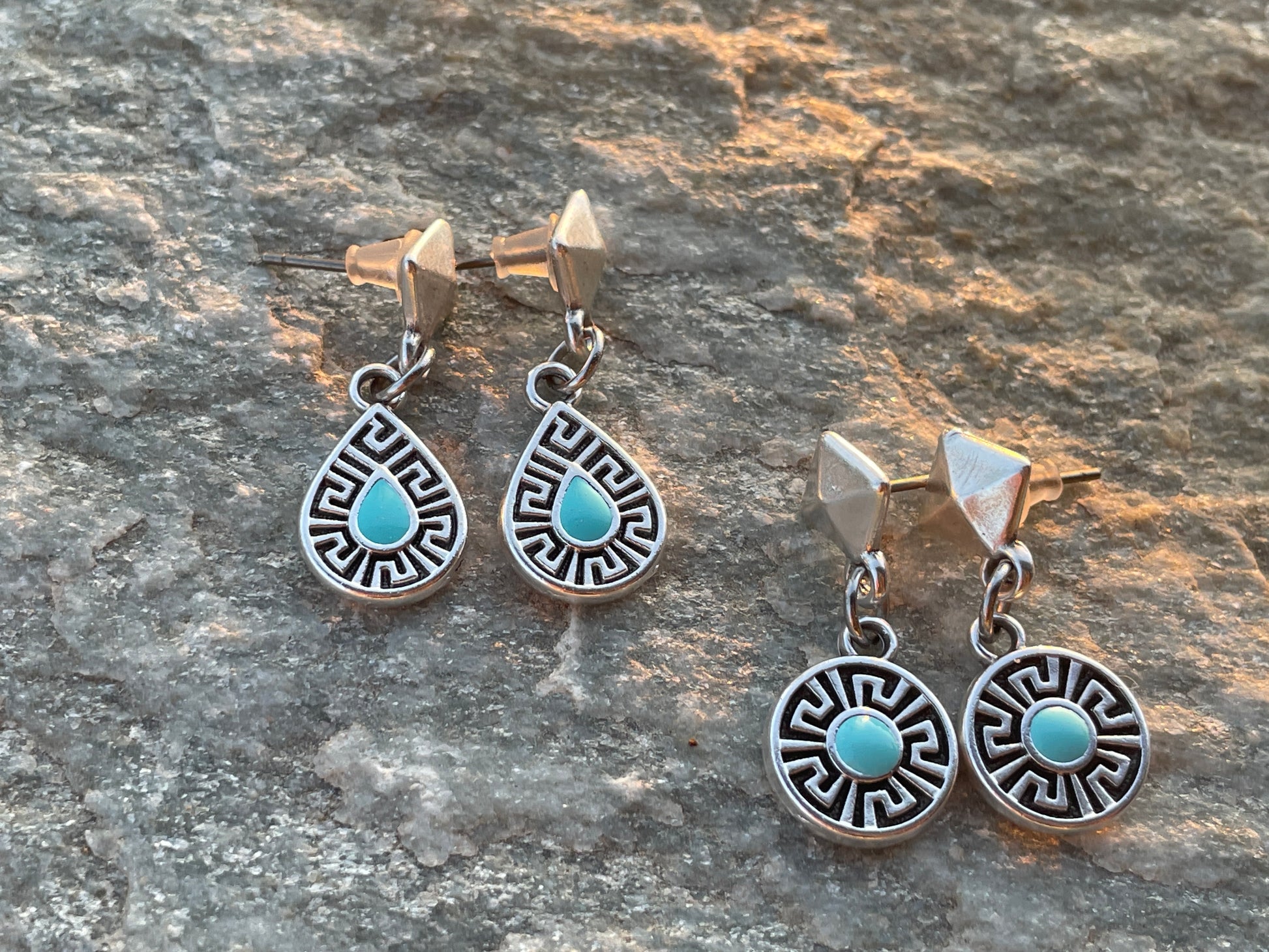 Pair of silver earrings with turquoise stones on a stone surface