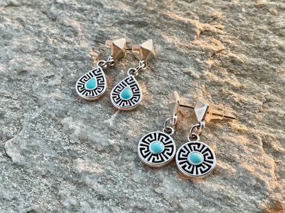 Pair of silver earrings with turquoise stones on a stone surface