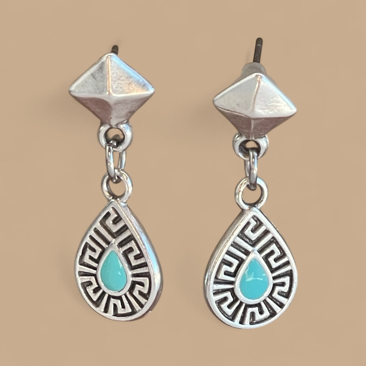 Silver earrings with turquoise drops on a beige background