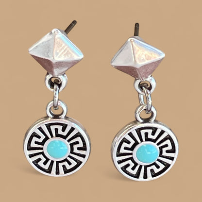 Pair of silver earrings with turquoise stones on a beige background