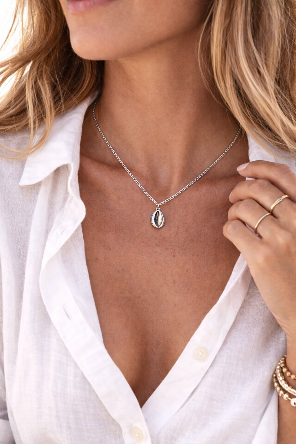 Minimalist stainless steel cowrie shell necklace with a polished silver finish, inspired by the sea and perfect for everyday beach style.