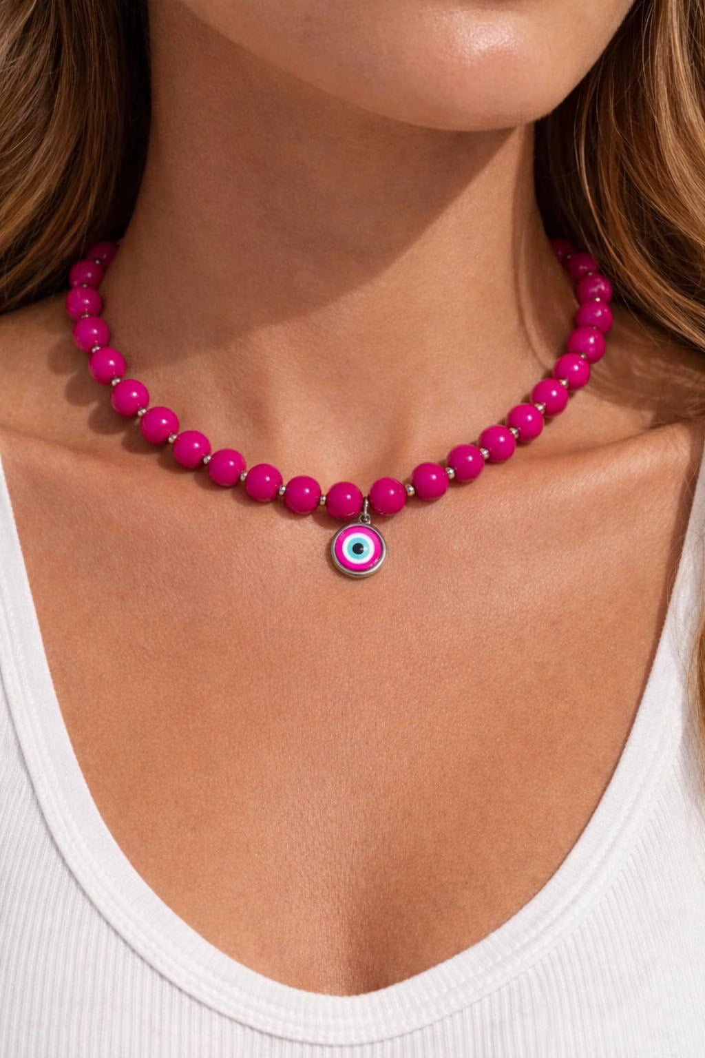 Close-up of a woman wearing a pink beaded necklace with an evil eye charm.