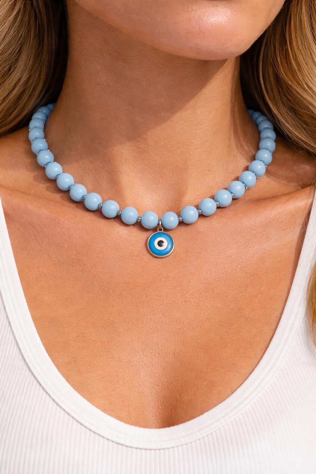 Necklace with blue beads and a circular pendant worn by a person.