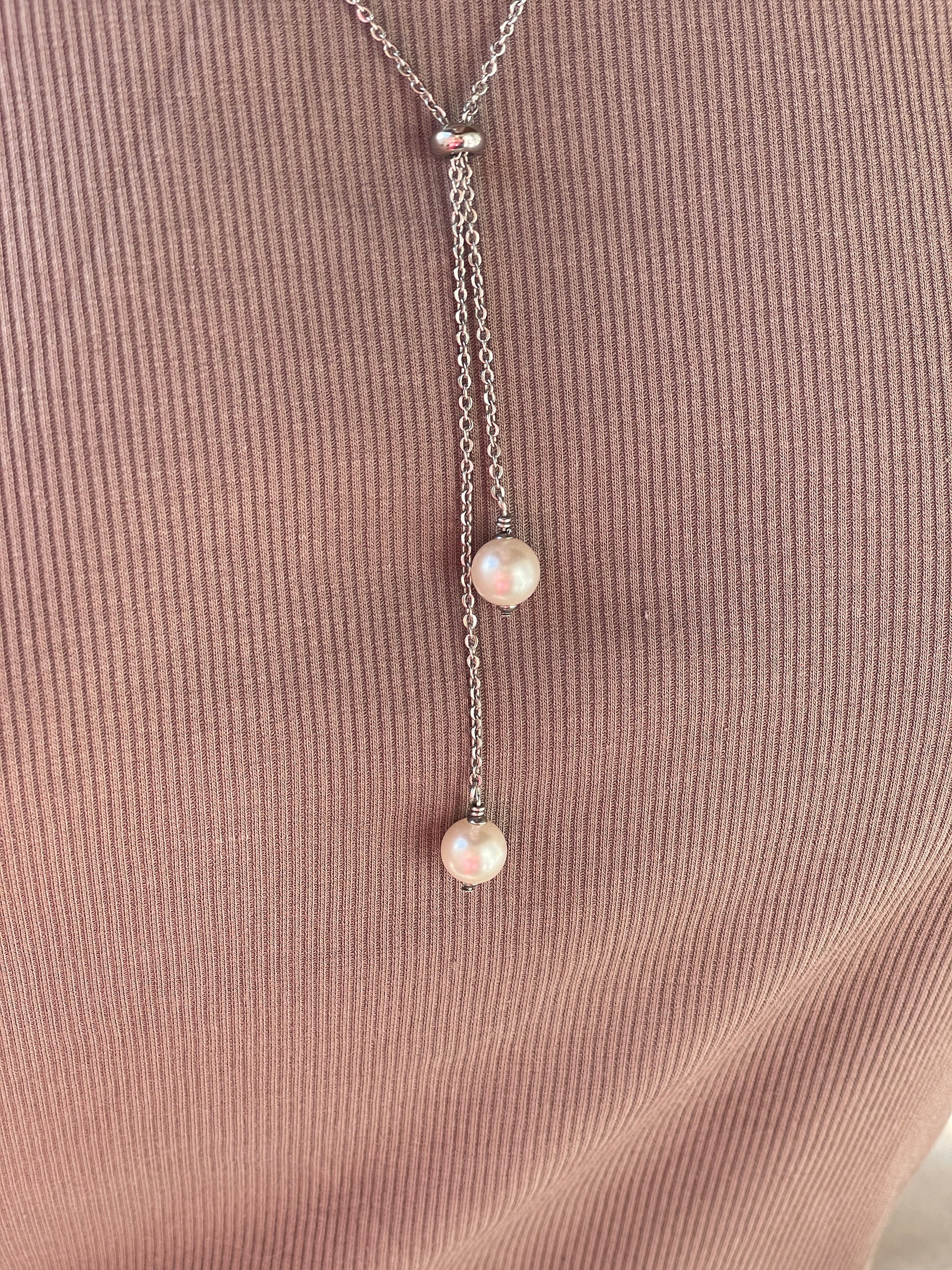 Silver necklace with three pearls on a textured brown surface