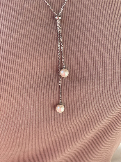 Silver necklace with three pearls on a textured brown surface