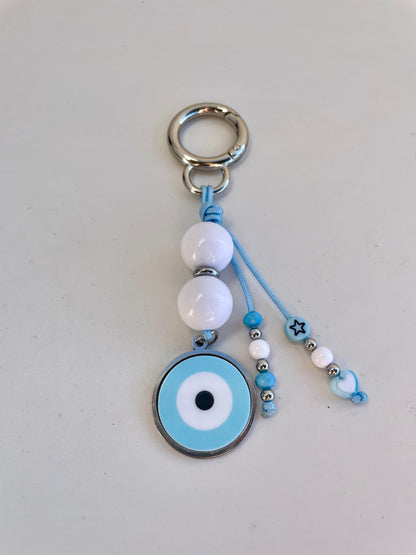Keychain with blue evil eye charm and beads on a light gray background